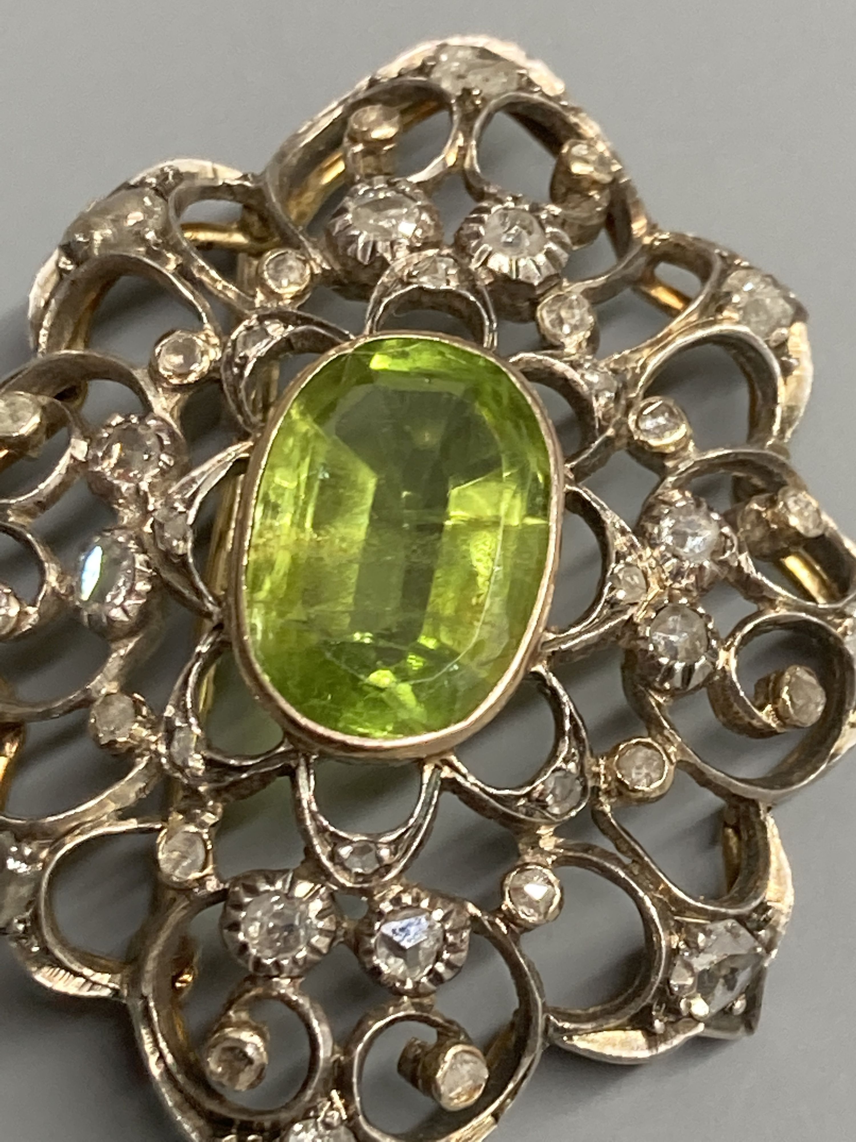 An early to mid 20th century Austro-Hungarian? white and yellow metal peridot and diamond set brooch, 38mm, gross 9 grams.
